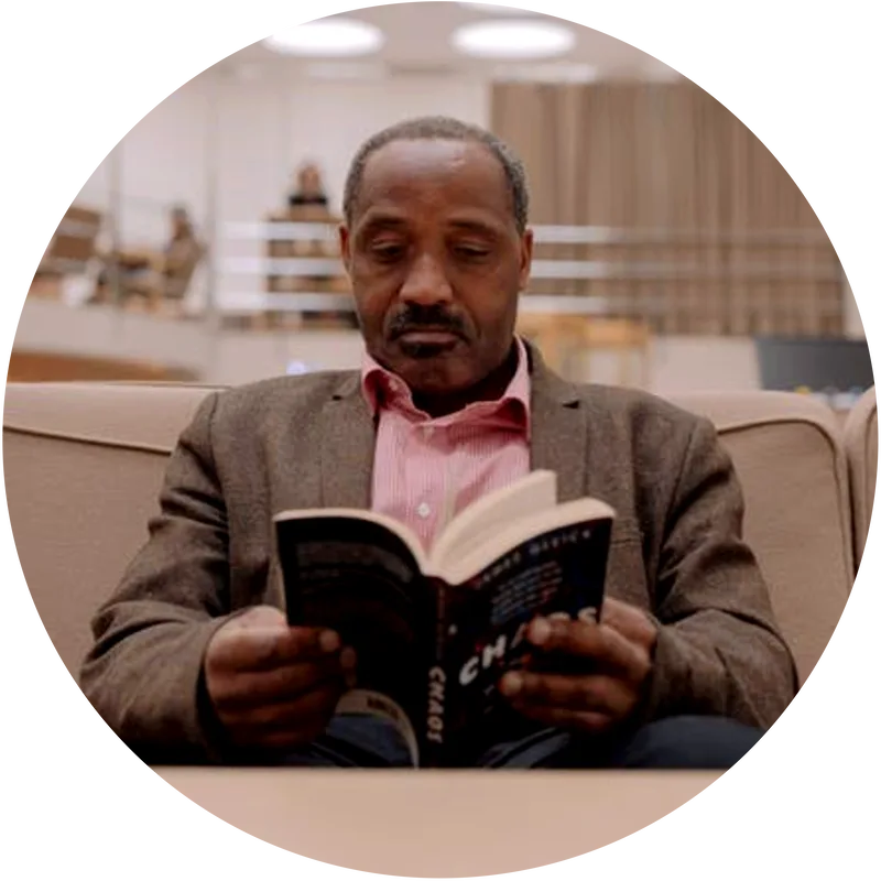 Picture of a man reading a book in a library.