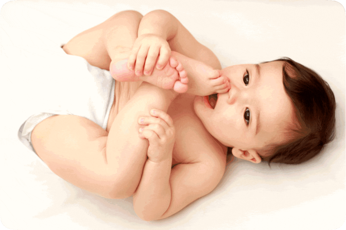 Picture of a baby lying on its back and trying to get its toes into its mouth.