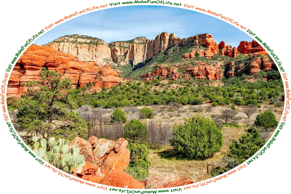 Picture of a desert with exposed red and tan rock outcroppings, during the growing season, with green leafy shrubs and cactuses, a hazy blue sky above, and the words, ‘Visit www.MakeFunOfLife.net.’