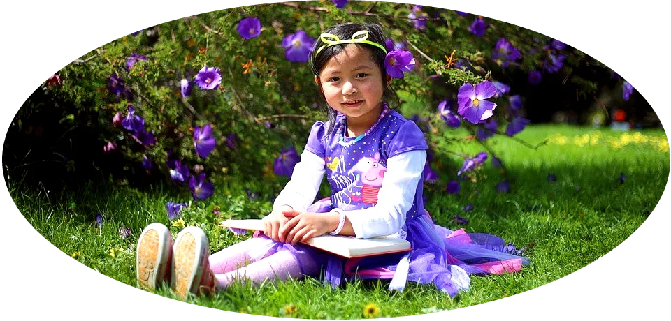 Picture of a girl with a book, sitting in a grassy area.