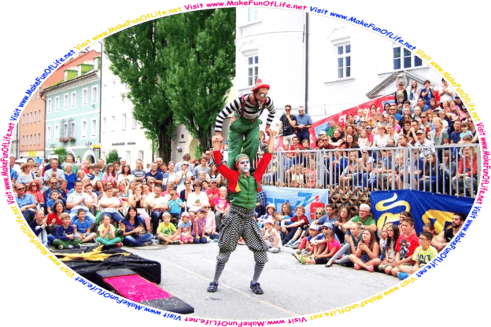 Picture of a clown standing on the shoulders of another clown as they are about to do a stunt with a springboard, while an audience watches, and the words, Visit www.MakeFunOfLife.net.