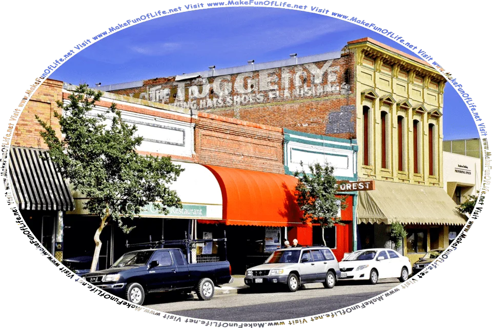 Picture of a two-lane street in the town of Ukiah, with cars parked along it, small shops, green leafy shade trees, a blue sky with a slight white cloud haze overhead, and the words, Visit www.MakeFunOfLife.net.