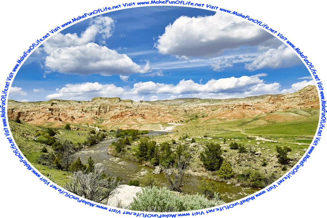 Picture of a wilderness area with a river having green scrub brush and green grass along its banks and high bluffs of mostly exposed red rock outcroppings in the background, a blue sky with large fluffy white clouds overhead, and the words, ‘Visit www.MakeFunOfLife.net.’
