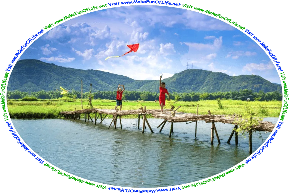 Picture of two boys flying kites as they run across a footbridge over a body of water, with green grass and leafy green trees covering hills in the background, a blue sky with fluffy white clouds overhead, and the words, ‘Visit www.MakeFunOfLife.net.’